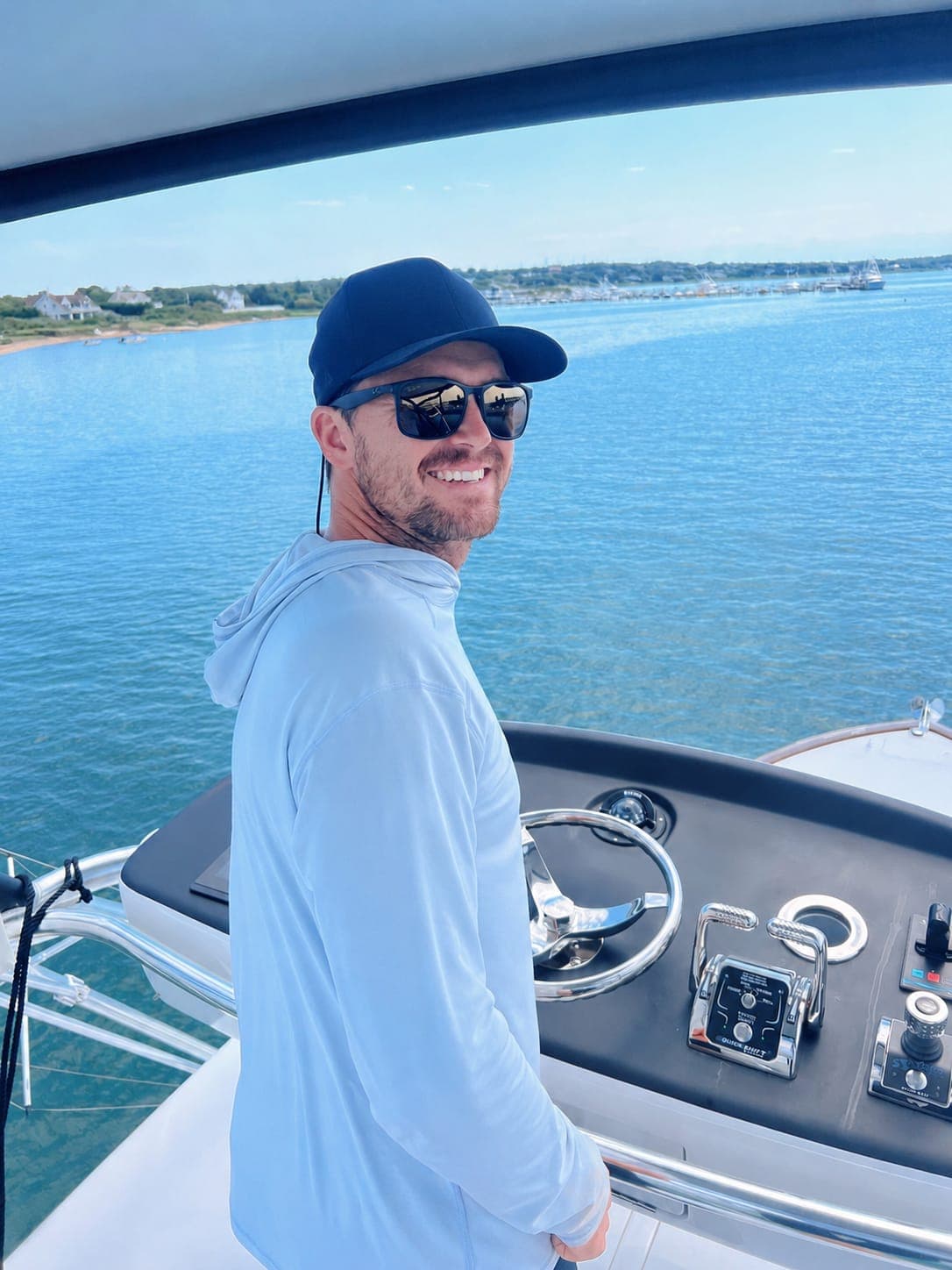 Garreth smiling at the console of a centre-console boat on flat water.