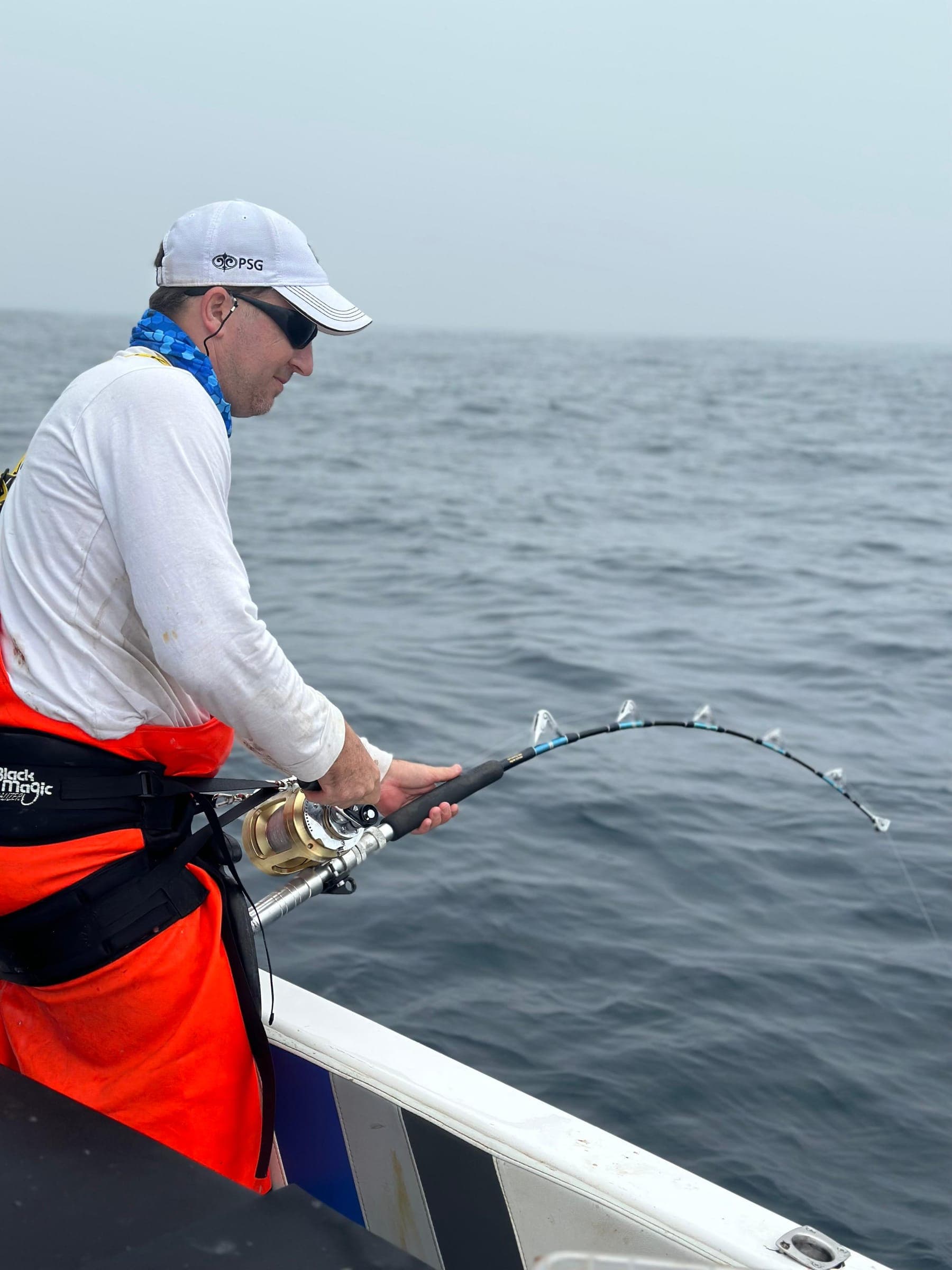 An angler working a fish in flat grey overcast conditions with almost no swell.