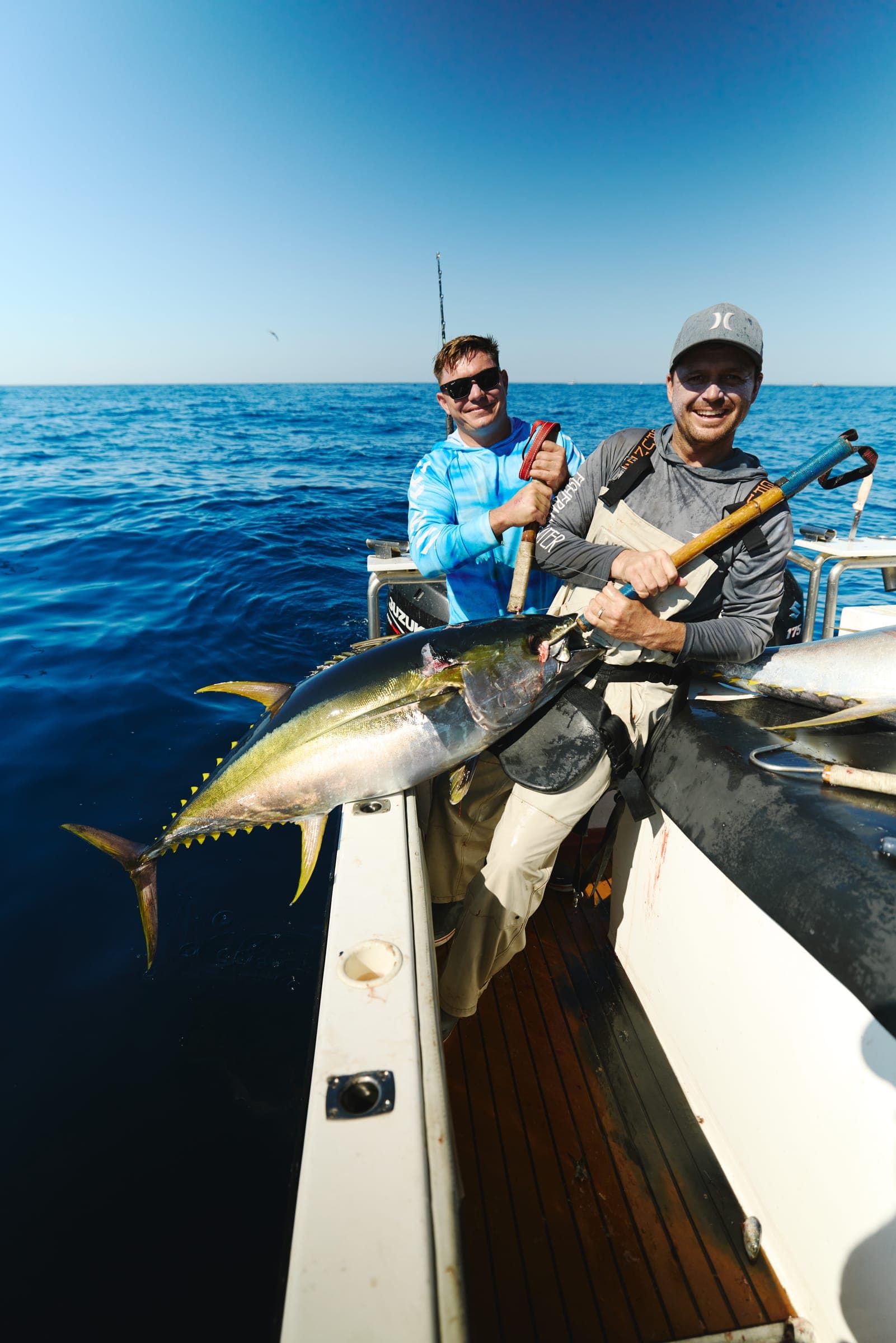 A yellowfin tuna held level at the rail by two crew, moments after being landed.