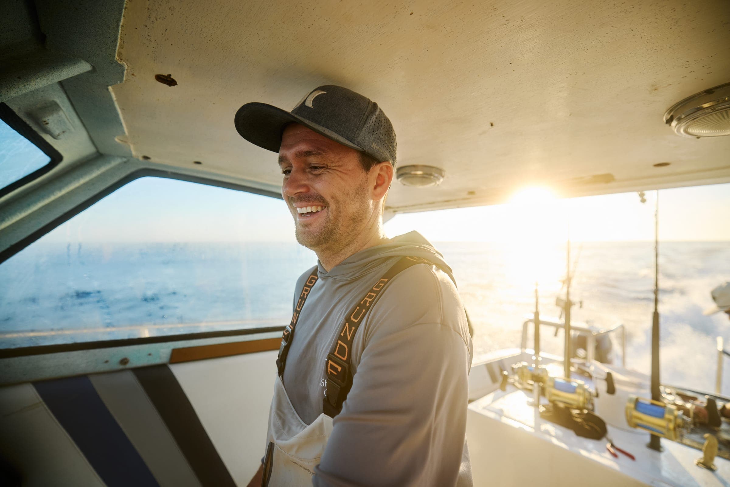 Captain Garreth at the helm of Benguela, backlit by low sun on the run home.